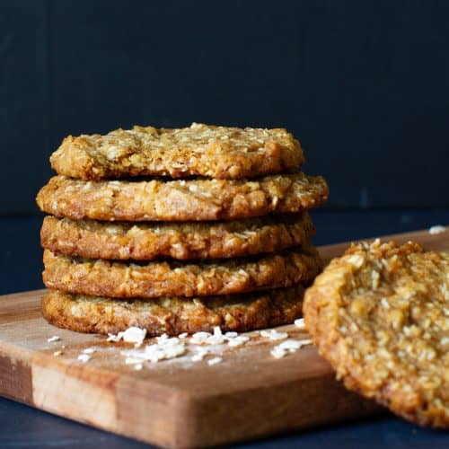 A stack of Anzac biscuits on a wooden board.