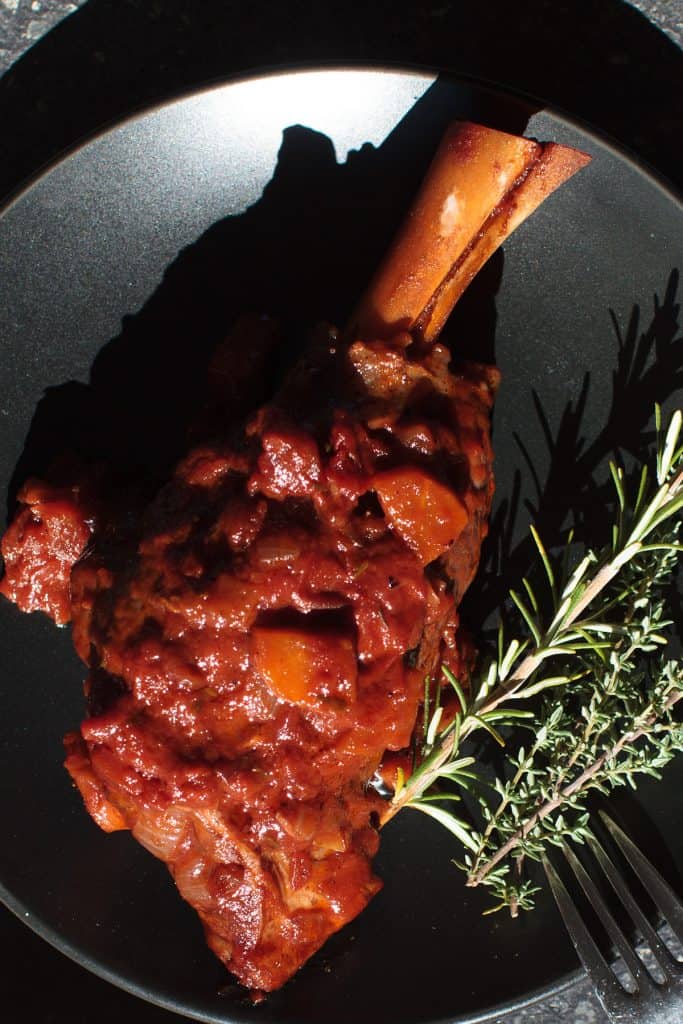 Moroccan lamb shank on a black plate.