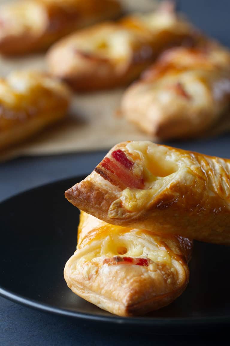 Two zoomed in cheese and bacon turnovers on a black plate