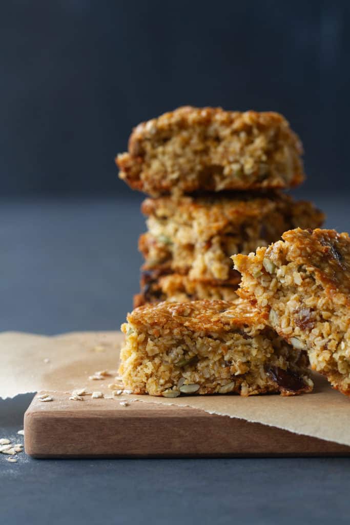 Five chewy granola bars on baking paper and a wooden board.