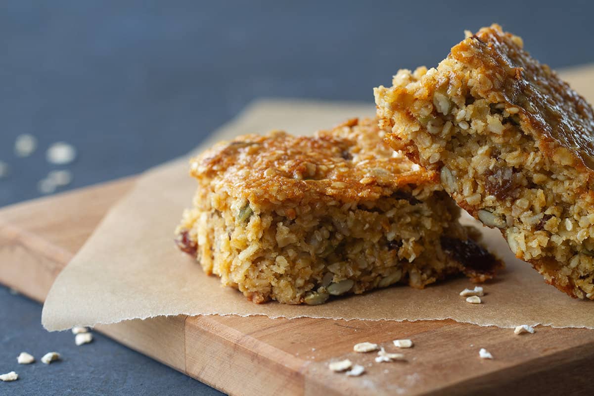 Two granola bars on baking paper and a wooden board.