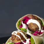 Two meatball wraps on a black plate.
