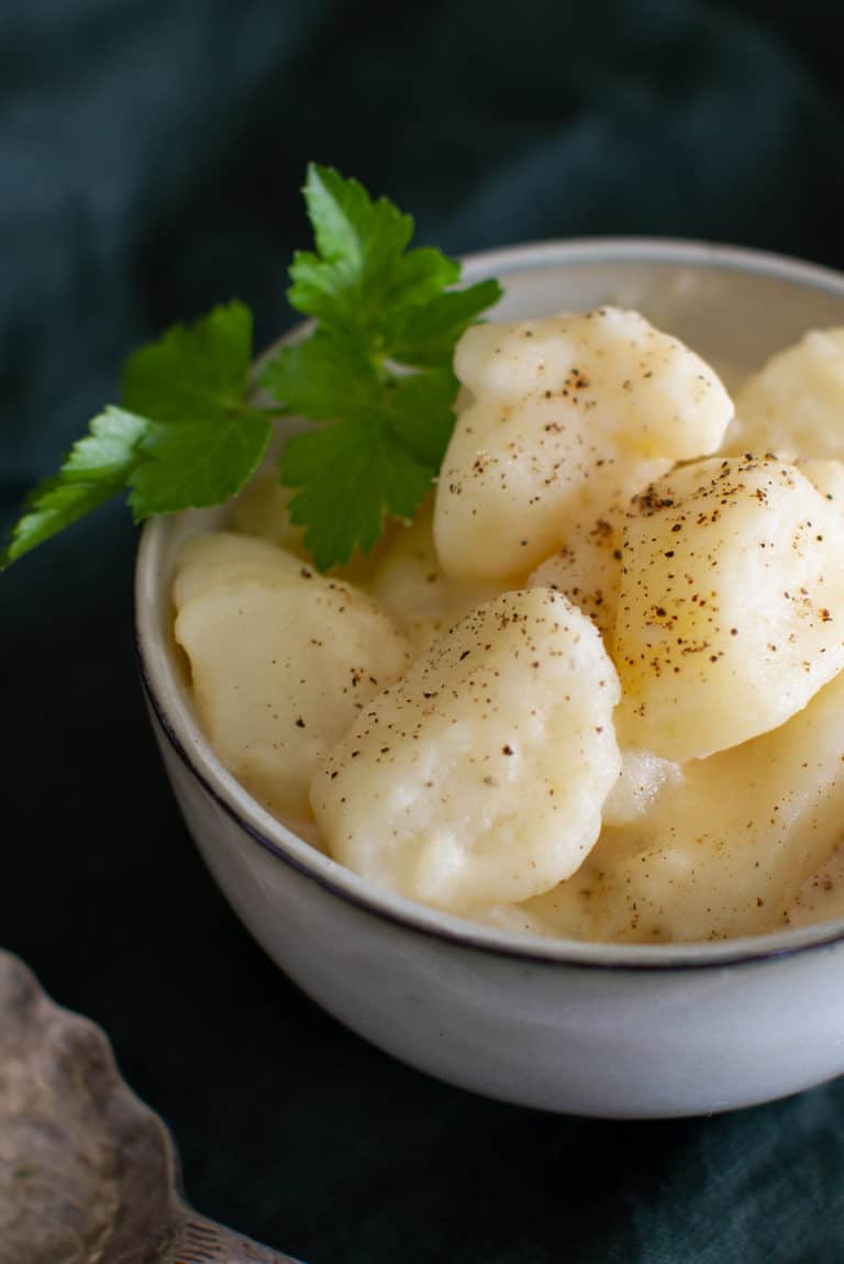 A small bowl of stewed potatoes with parsley.