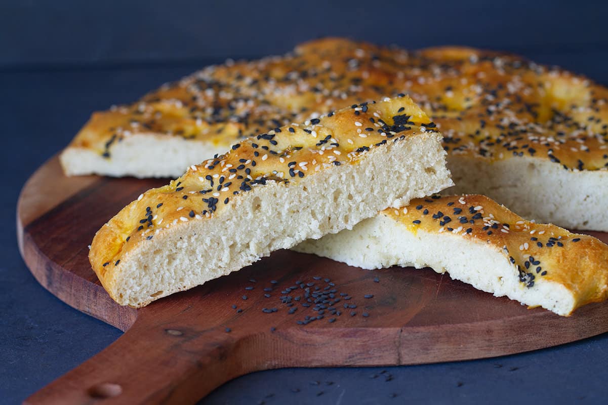 Small slices of Turkish pide bread on a round wooden board.