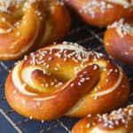 A metal cookie tray with snack size soft German pretzels. Dark background.