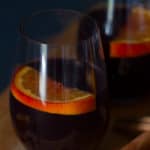 Two glasses of non-alcoholic mulled wine with orange slices in it. Moody scene.