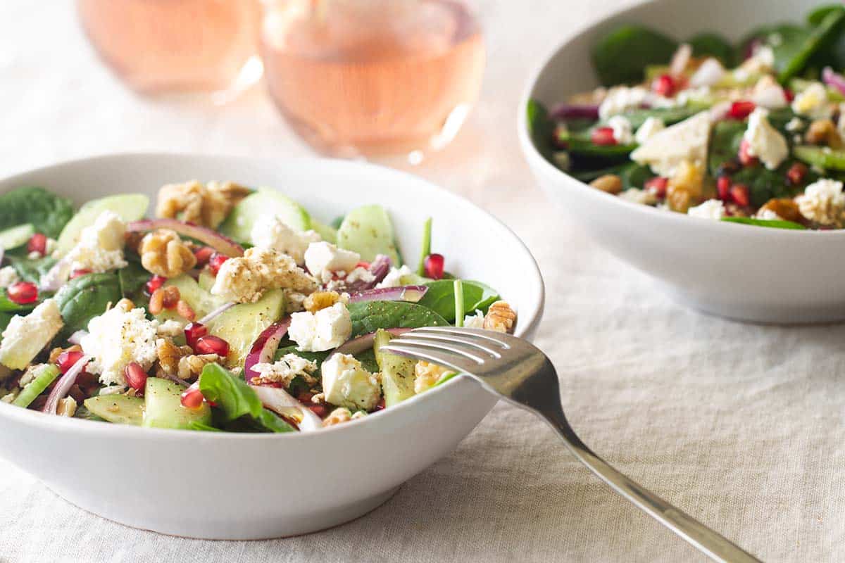 Two bowls with insalata mista next to glasses or rosé wine.