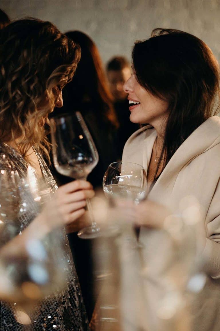 Two glamorous women chatting over a glass of wine.