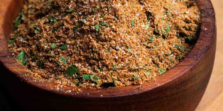 Chermoula spice blend in a wooden bowl which sits on a wooden board.