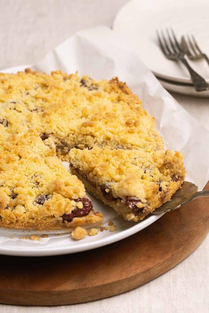 A Streuselkuchen on a plate that sits on a wooden board.