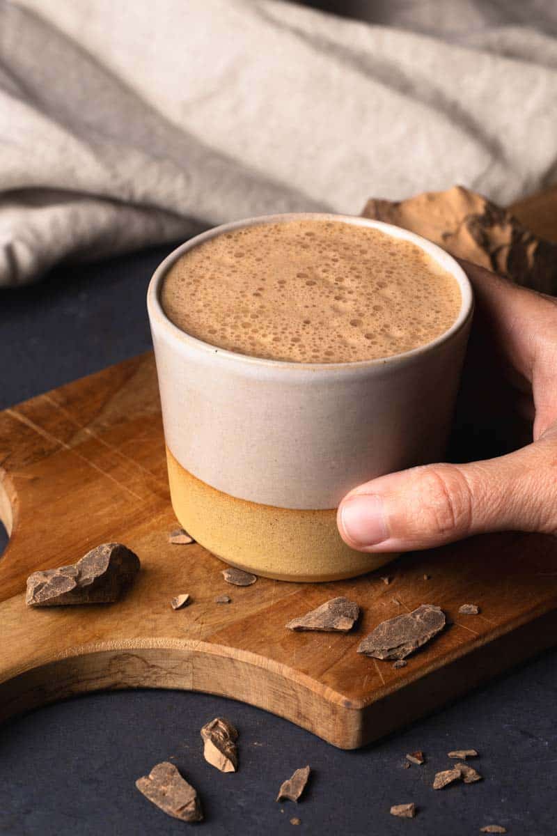 A cup of ceremonial cacao on a wooden board.