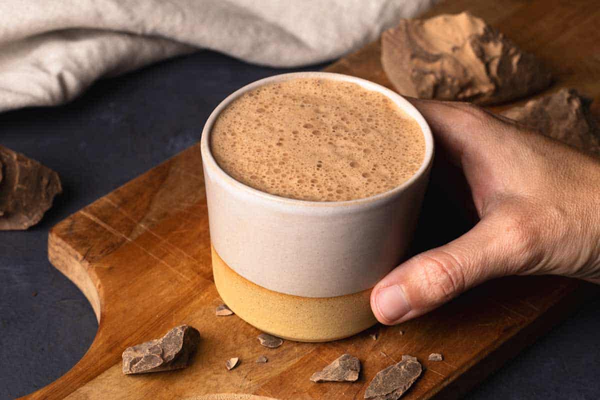 A cup of ceremonial cacao on a wooden board.