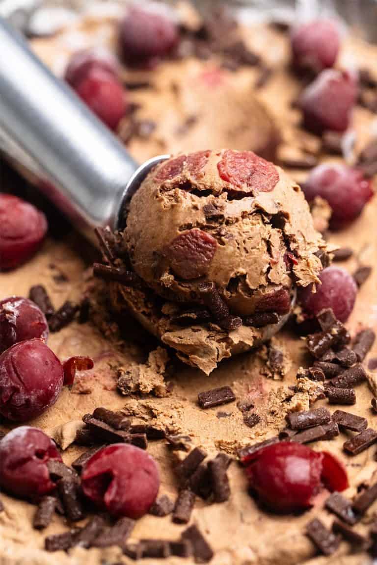 A close-up of condensed milk chocolate cherry ice cream being scooped.