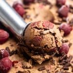 A close-up of condensed milk chocolate cherry ice cream being scooped.