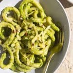 A bowl of pici pasta with creamy lemon pesto sauce next to a linen tea towel.