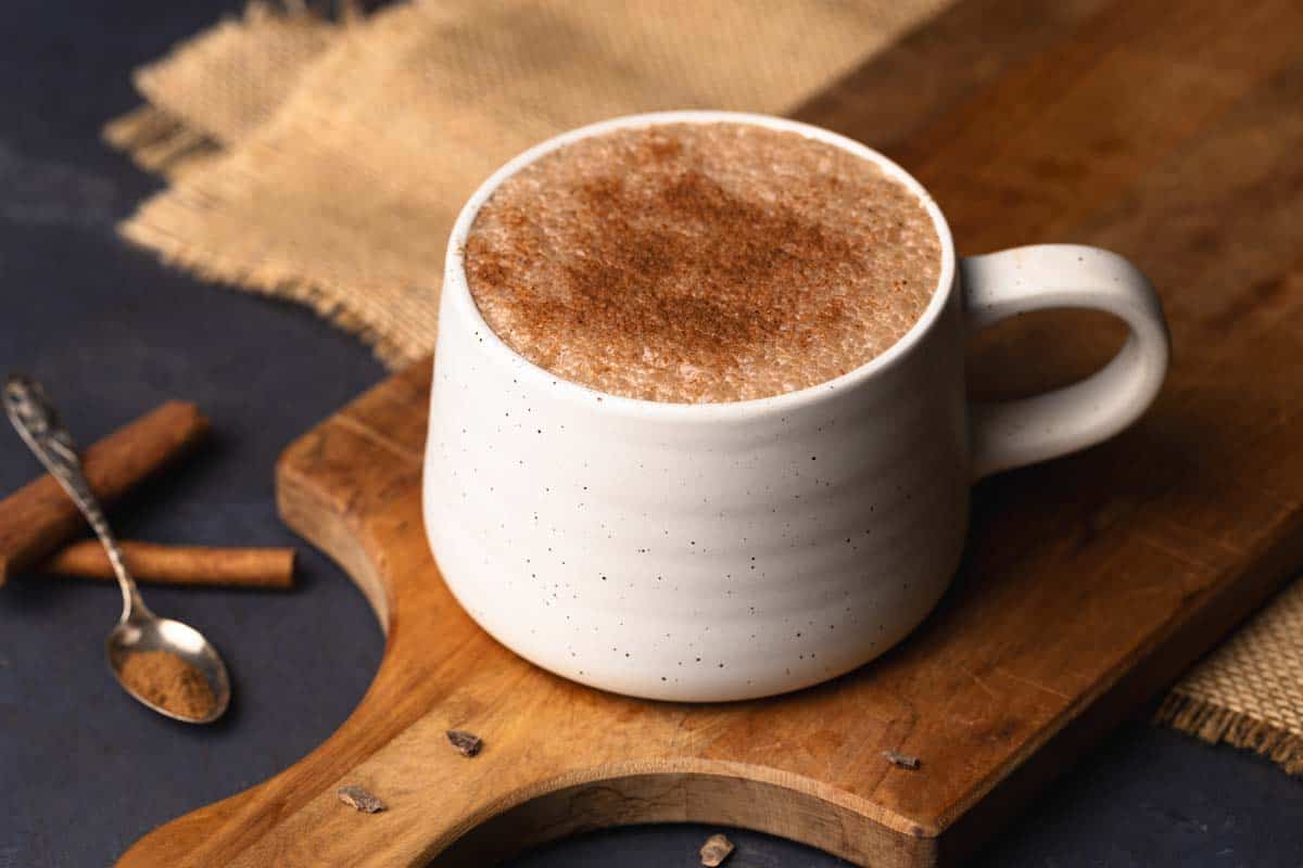 A mug of pumpkin spiced hot chocolate on a wooden board.