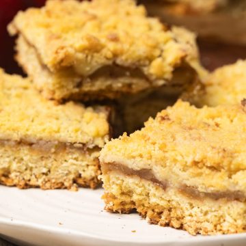 Apple bars on a white plate next to red apples.