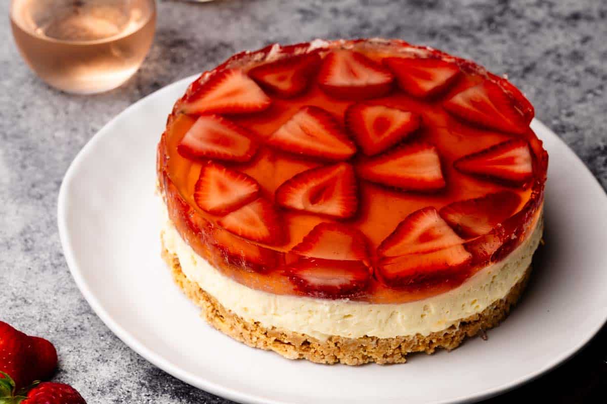 A Strawberry Rosé Cake on a white plate next to Rosé glasses.