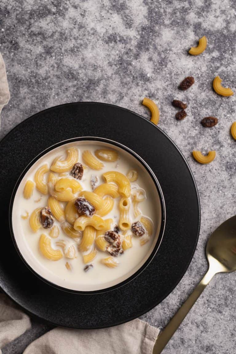 A bowl of milk soup with pasta on a black plate.