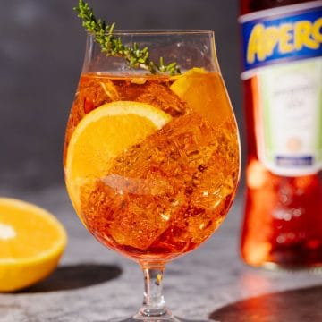 A Rosé Aperol Spritz Cocktail next to an Aperol bottle.