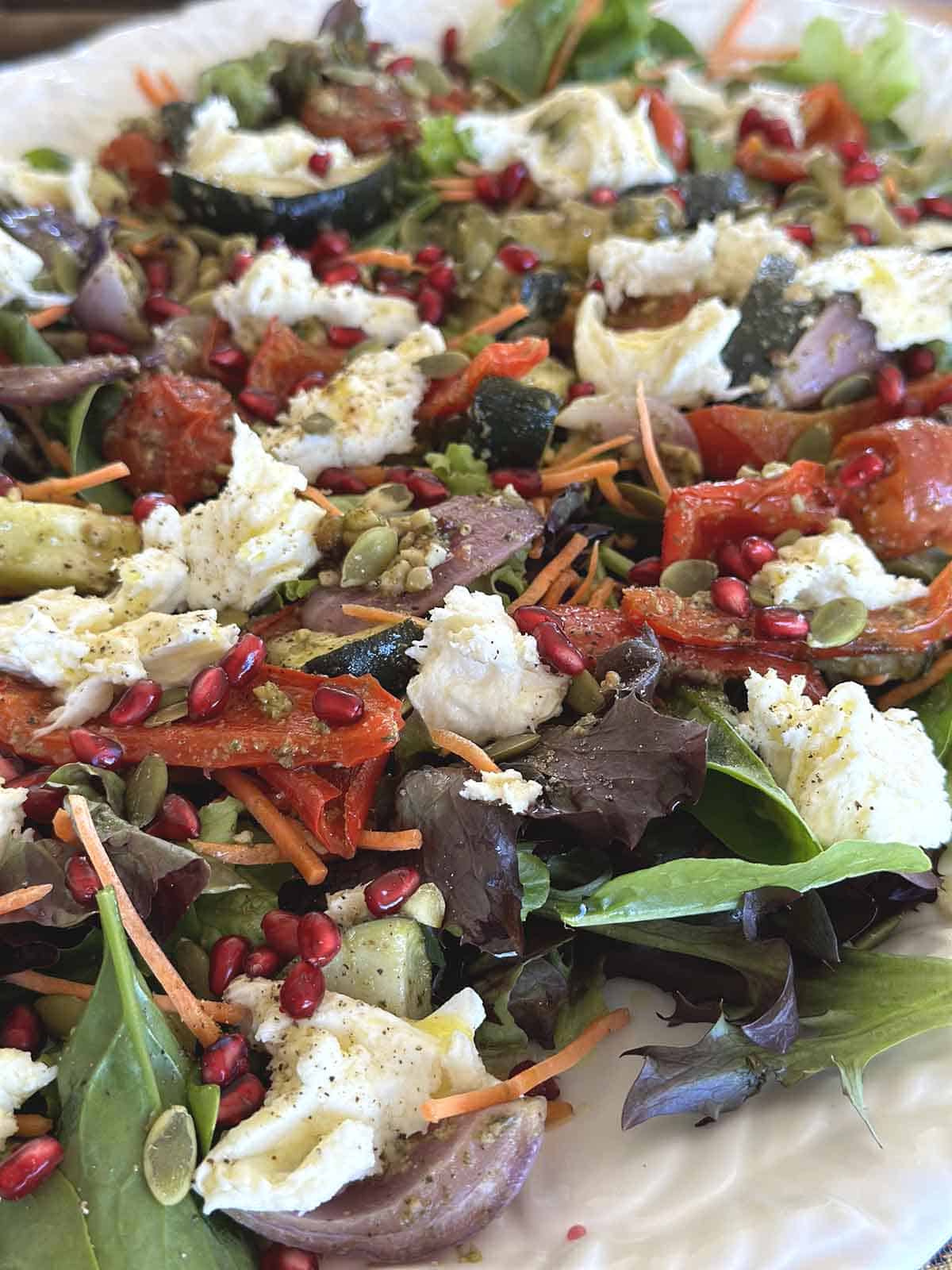 Pesto roasted vegetables in a salad with mozzarella, pomegranate ariels, and carrots.