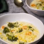 Two bowls filled with broccoli cheese soup with noodles.