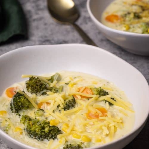Two bowls filled with broccoli cheese soup with noodles.