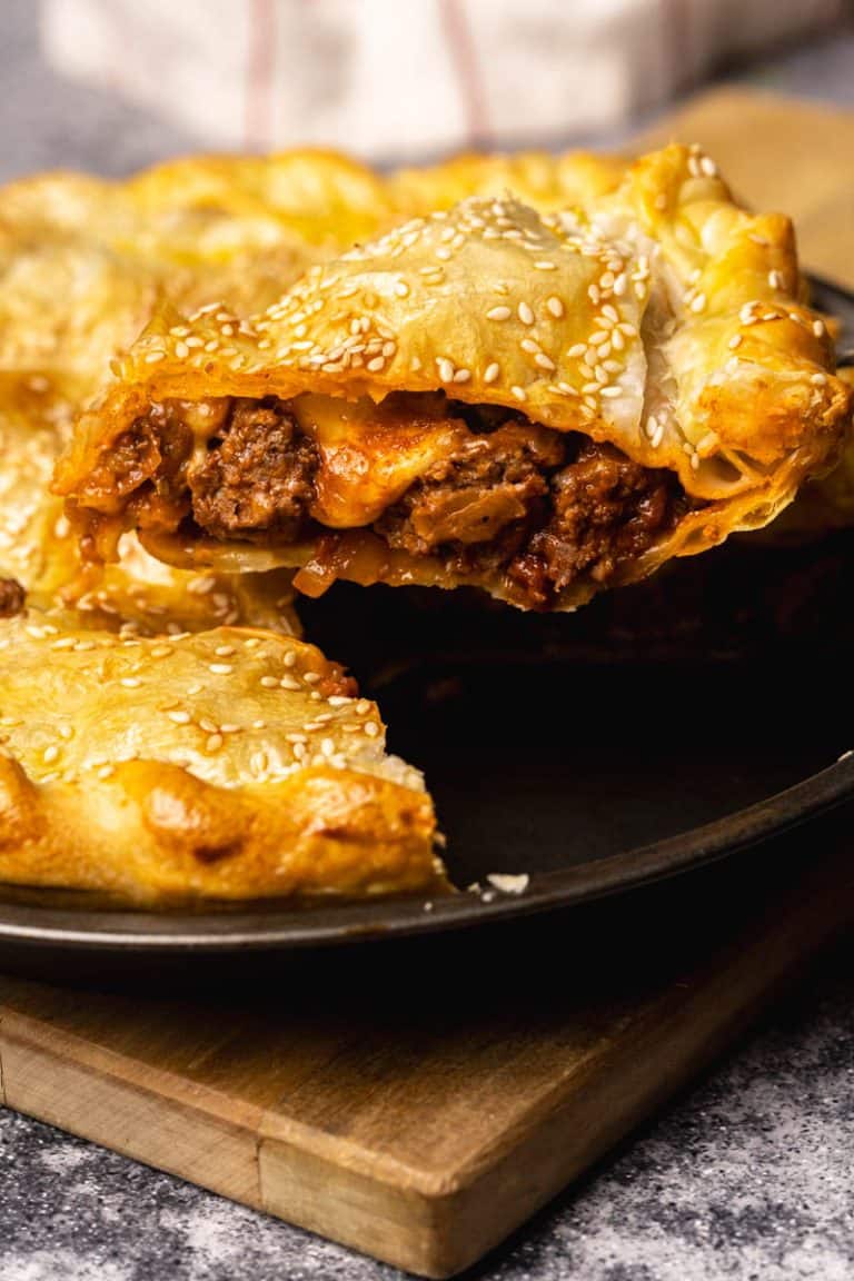 A slice of ground beef pie being lifted from the pie dish.