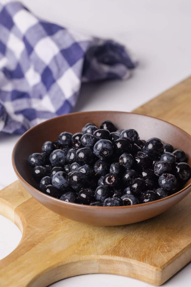 Macerated blueberries in a brown bowl which is sitting o