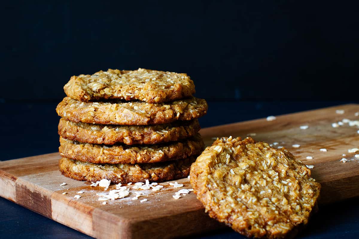 A stack of Anzac biscuits on a wooden board.