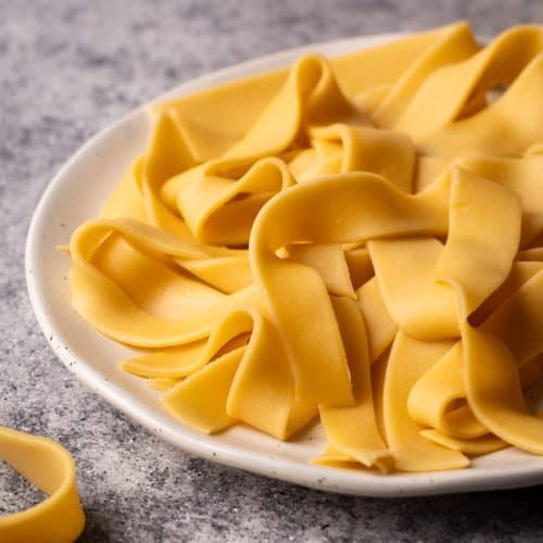 Fresh ribbon pasta on a white plate.