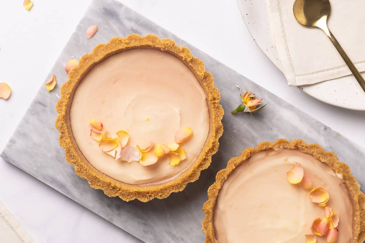 Two mini cheesecake tarts on a marble plate.