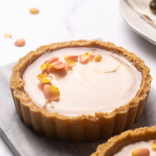 Two mini cheesecake tarts on a marble plate.