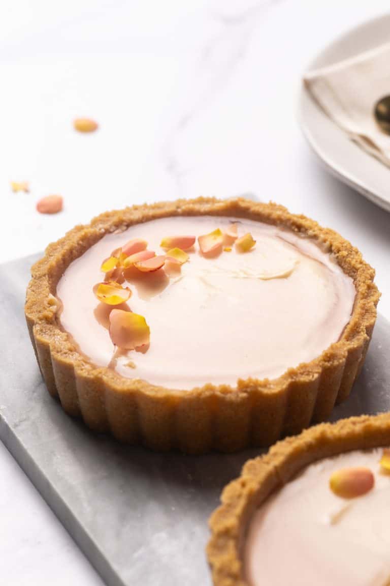 Two mini cheesecake tarts on a marble plate.