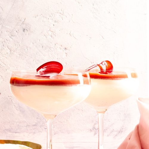 Two champagne coupes filled with vanilla panna cotta and rhubarb coulis.
