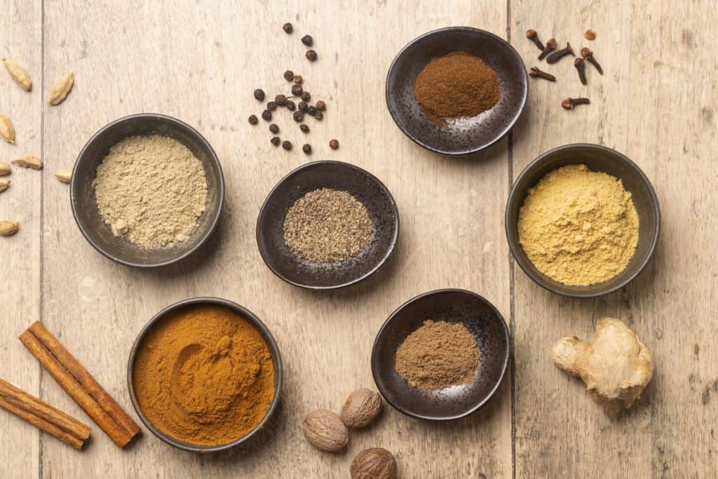 Ground and whole spices laid out on a wooden surface.