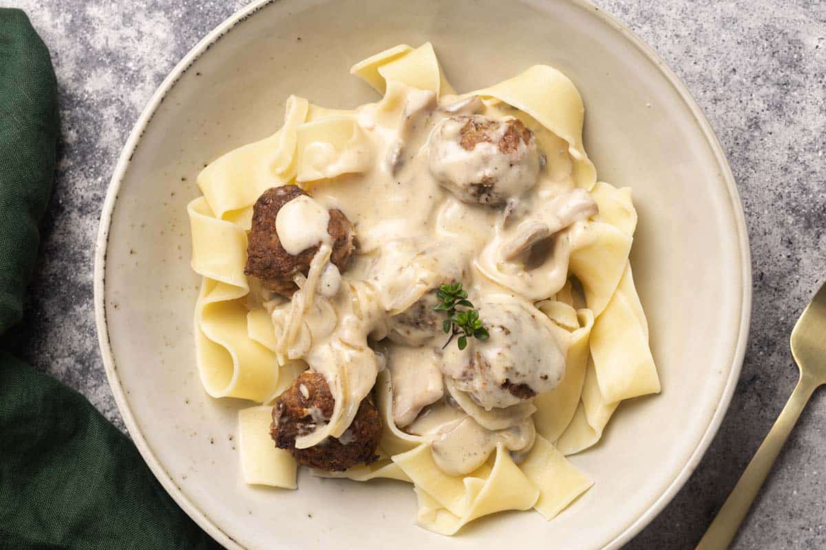 Meatballs in a creamy sauce added to large fettuccine.