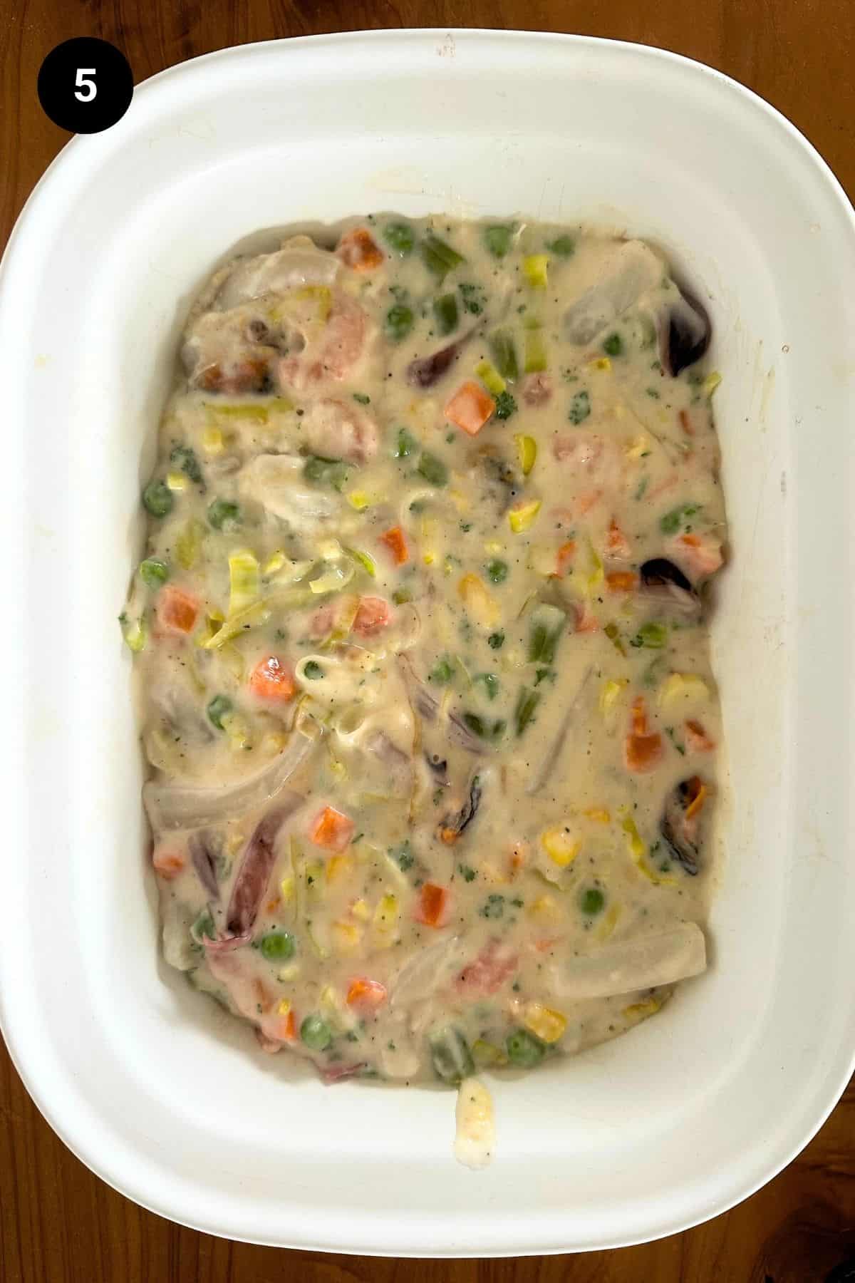 A casserole dish filled with seafood pie, filling layer shown.
