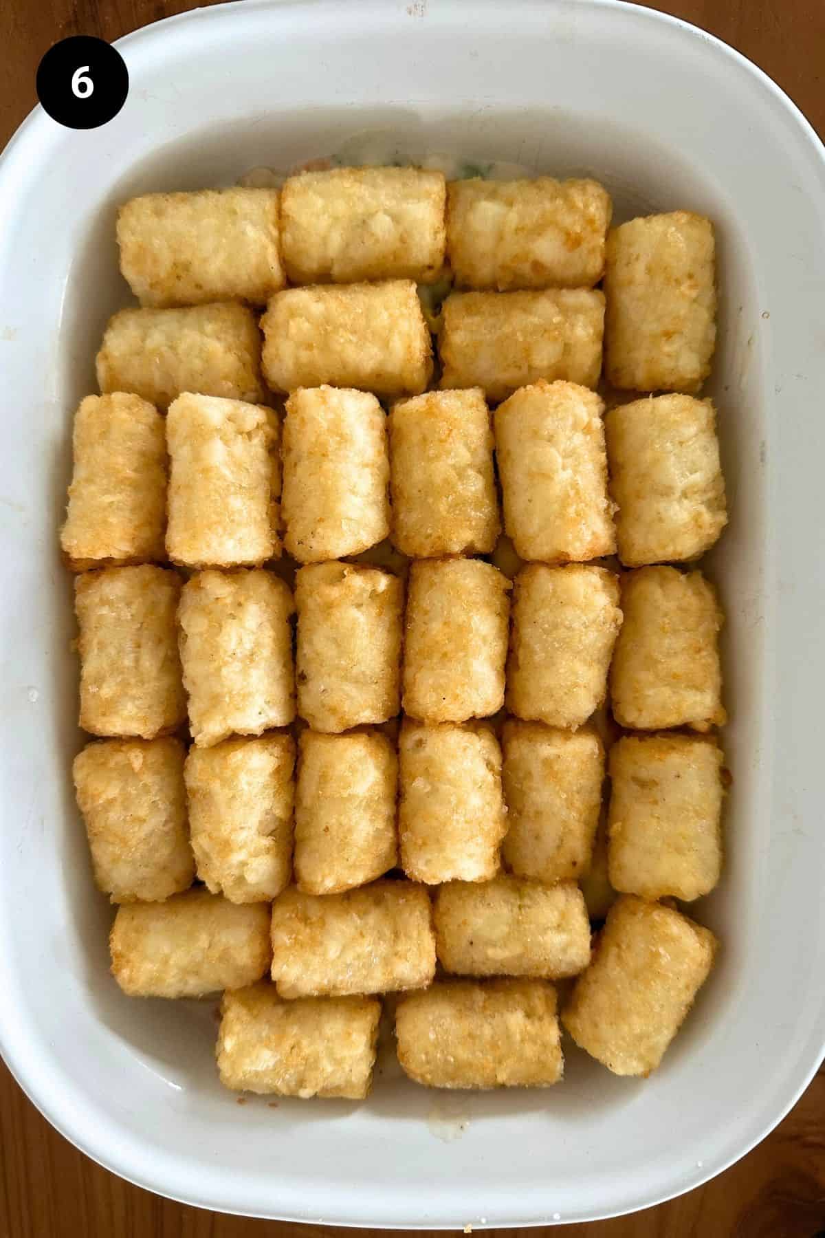 A casserole dish filled with seafood pie, layer of mini hash browns shown.