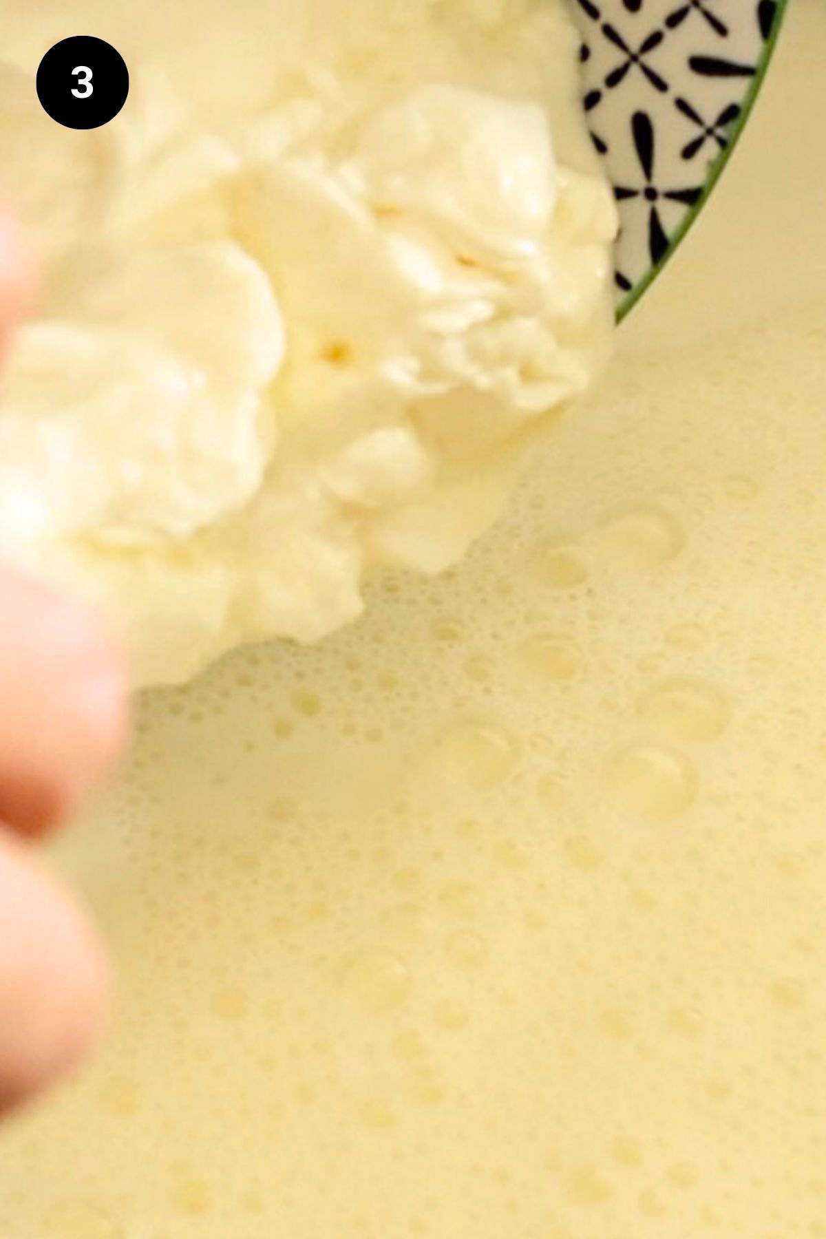 Yogurt being added to heated milk.
