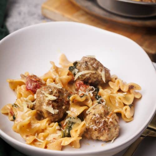 Marry me meatball pasta in a white pasta bowl next to the pan.