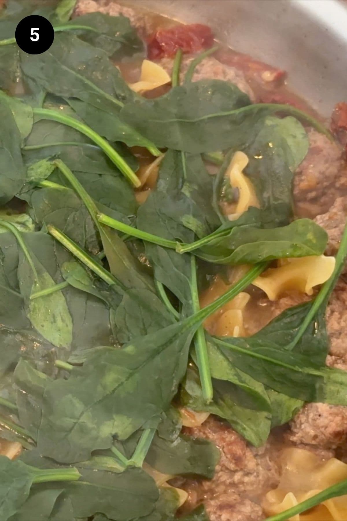 Wilted spinach on top of the pasta and meatballs.