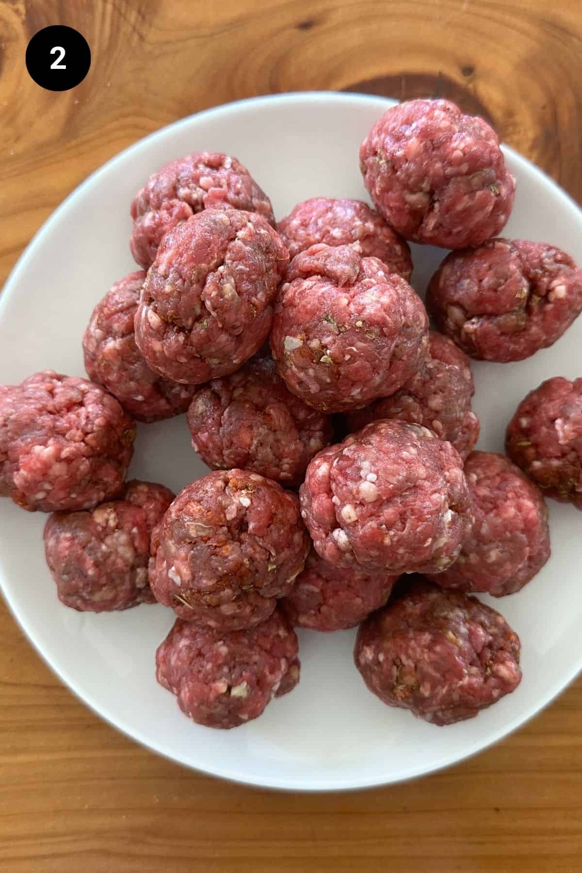 Formed beef meatballs before cooking on a plate.