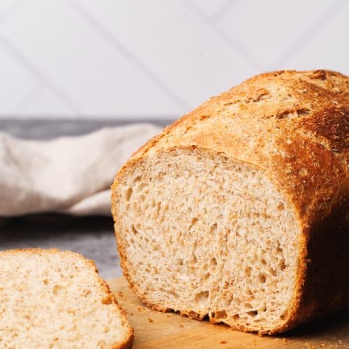 A loaf of cold fermented bread cut open on a wooden board.
