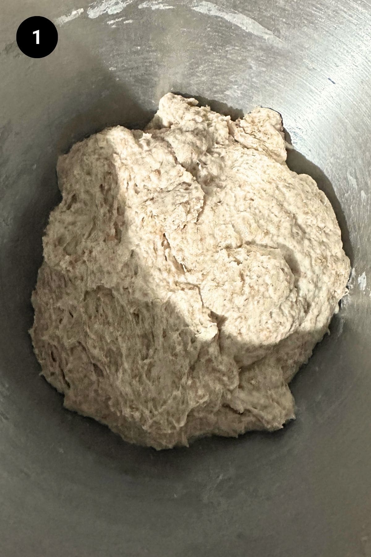 Bread dough in a stainless steal bowl.