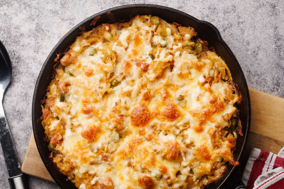 Sauerkraut casserole in a cast iron skillet on a wooden board.