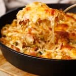 Sauerkraut casserole being scooped out of a cast iron skillet.