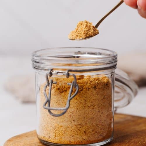 Milk powder being scooped out of a glass container.