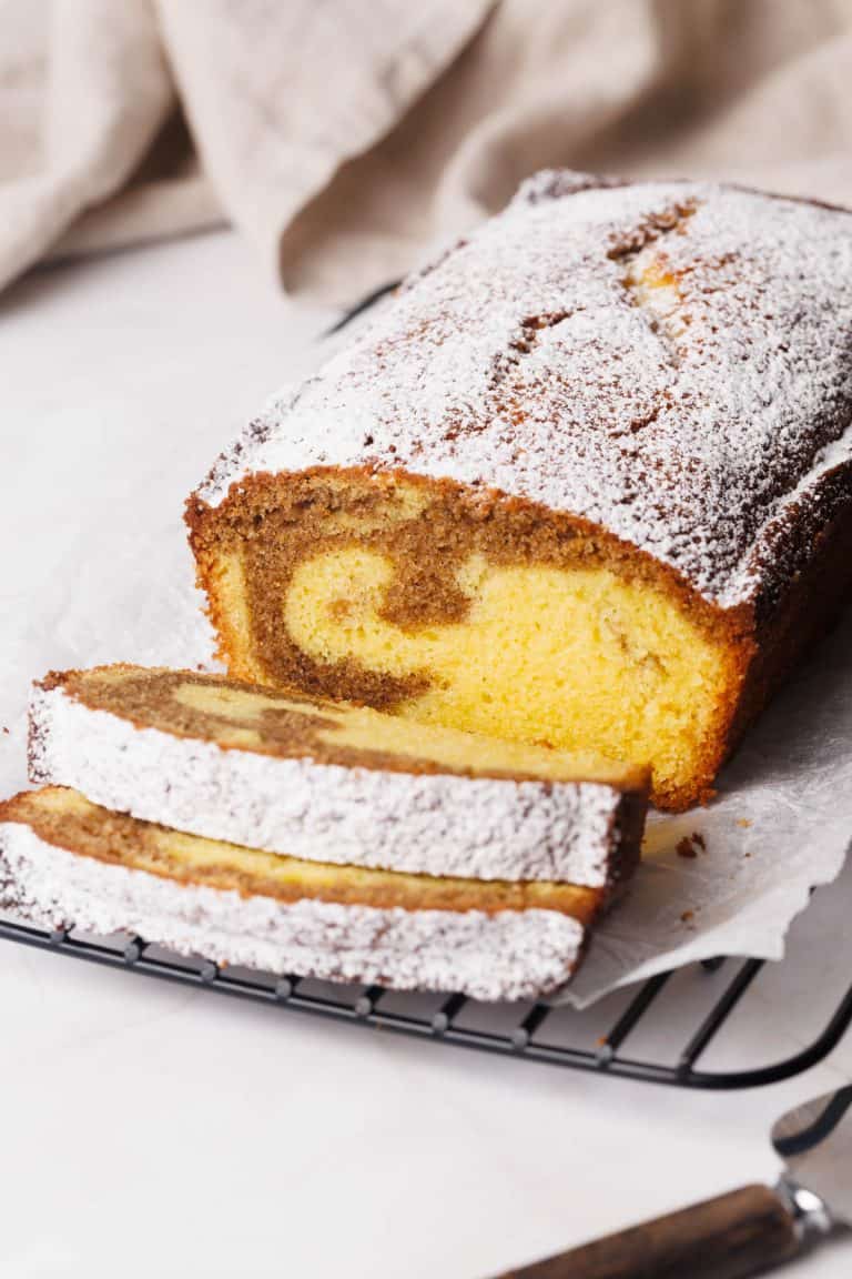 Cinnamon pound cake sliced on a wire rack next to a tea towel.