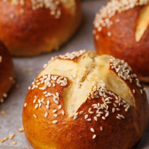 Pretzel buns on a baking tray just after being baked.